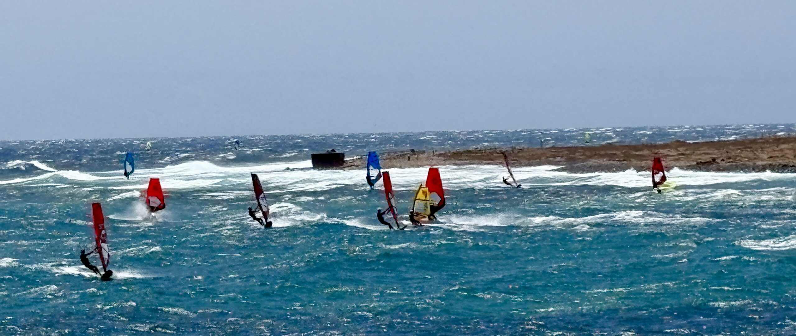 Mehrere Windsurfer fahren bei starkem Wind und hohen Wellen vor Pozo Izquierdo