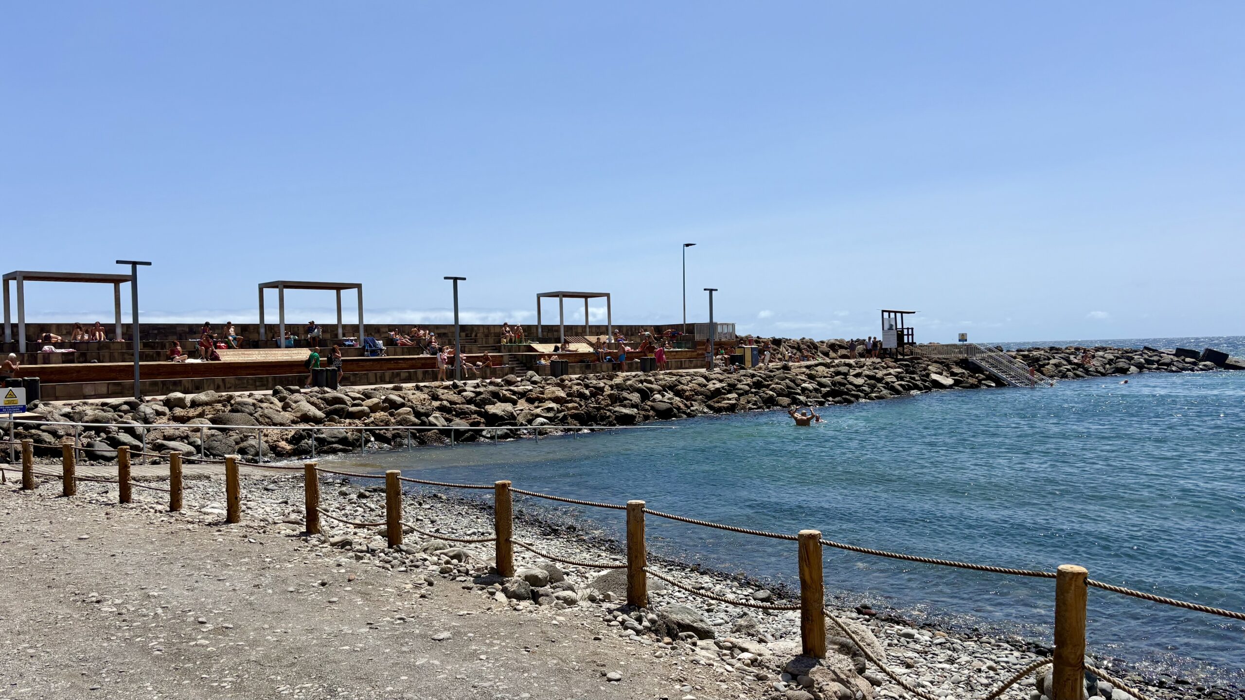 Geschützter Badebereich mit steiniger Küste und terrassenartigem Zuschauerbereich in Pozo Izquierdo